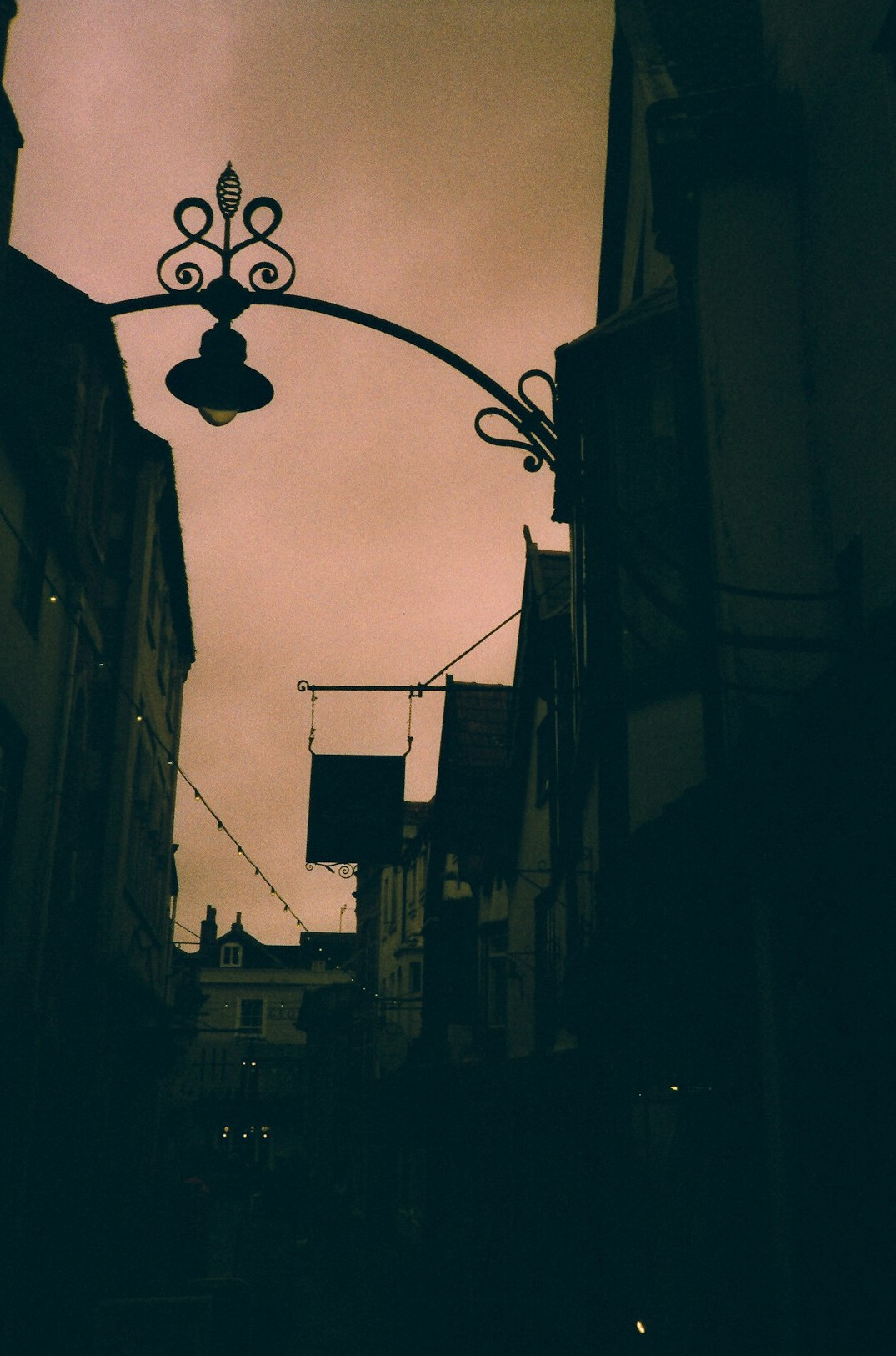 Old city street at dusk with warm street lamps